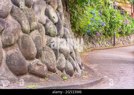 tokio, japan - 15 2021. juni: Nahaufnahme einer Trockensteinmauer entlang des kurvigen Abhangs der für ihre blo berühmten Asuka-no-komichi-Straße Stockfoto