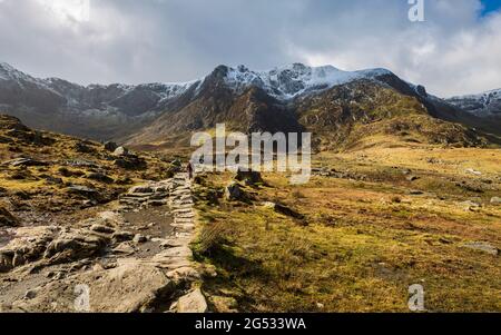 Der Steinweg, der zum Lake Idwal führt, und die schneebedeckten Berge von Snowdonia, Wales Stockfoto