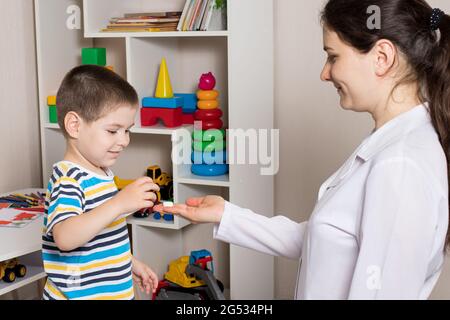 Eine Kinderärztin oder Krankenschwester gibt einem Kind eine weiße Vitaminpille. Nahrungsergänzungsmittel für Kinder, Vitamine. Stockfoto