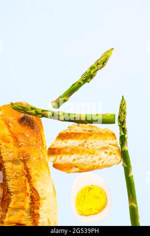 Frisch gegrilltes Brot, Spargel und Ei. Zum Frühstück gibt es Inridients. Gleichgewichtsschwimmende Lebensmittel. Balance Levitation Food. Vertikales Foto. Stockfoto