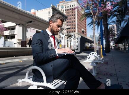 Reifer Mann Geschäftsmann in Anzug sitzen auf der Bank in der Stadt im Freien arbeiten online auf Laptop, Büro online Stockfoto