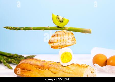 Frisches Brot, Spargel, Kiwi und Ei. Zum Frühstück gibt es Inridients. Gleichgewichtsschwimmende Lebensmittel. Balance Levitation Food. Stockfoto