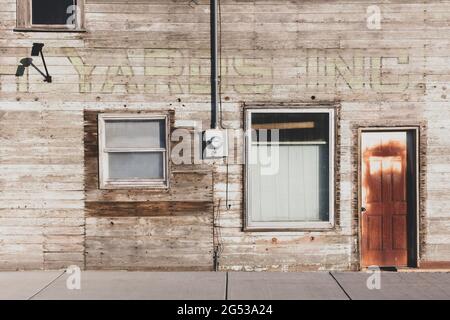 Altes Holzgebäude an der Hauptstraße, verrostete Tür und vertäfelte Fenster. Stockfoto