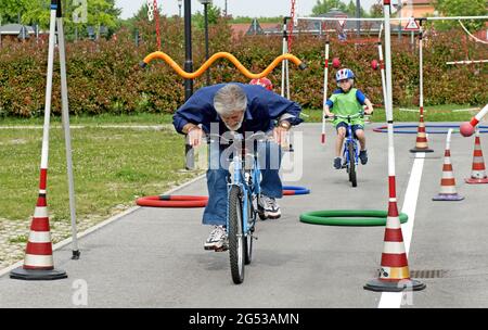 Großväter, die den Kindern Fahrrad-Straßenregeln beibringen, in Civitas Vitae, einem Seniorenresidenz, in Padua, Italien Stockfoto