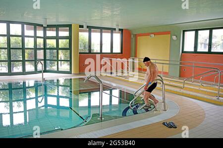 Ein älterer Mann tritt in ein Schwimmbad ein, in Civitas Vitae, einem Seniorenresidenz, in Padua, Italien Stockfoto