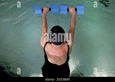 Ältere Frau, die in einem Schwimmbad in Civitas Vitae, einem Seniorenresidenz, in Padua, Italien, Wasserfitness übt Stockfoto