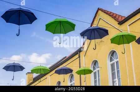 Bunte Regenschirme vor einem gelben Gebäude in Meppen, Deutschland Stockfoto