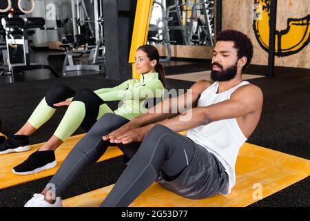 afroamerikanischer Mann und junge Frau machen abs-Übungen auf Fitnessmatten Stockfoto