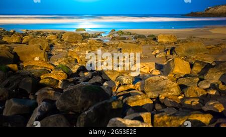 Schatten eines Paares, das sich nachts mit einer Meereslandschaft und einer Mondspiegelung küsst Stockfoto