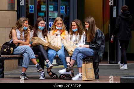 Dundee, Tayside, Schottland, Großbritannien. Juni 2021. UK Wetter: Ein heller Tag mit einer kühlen Brise durch Nordostschottland mit Temperaturen bis zu 15 Grad Schottische Schulen haben heute für die Sommerferien geschlossen und viele Anwohner nehmen sich den Tag aus, um das Wetter zu genießen und mit Freunden zu unterhalten. Fünf junge Frauen, die vor dem Overdate-Einkaufszentrum sitzen, nachdem sie einen Tag lang im Primark Retail Fashion Store im Stadtzentrum von Dundee einkaufen waren. Kredit: Dundee Photographics/Alamy Live Nachrichten Stockfoto