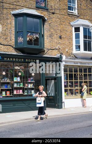 Menschen unterwegs an einem sonnigen Samstag vor den Geschäften von Harbour Books und Just Shoes in der Harbour Street, Whitstable, Kent, England, Großbritannien Stockfoto