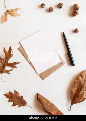 Rahmen aus verschiedenen Herbstblättern und Eicheln, Umschlag und Postkarte auf weißem Hintergrund. Draufsicht. Kopierbereich. Minimale Herbstzusammensetzung Stockfoto