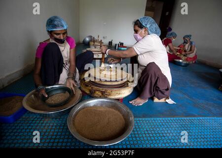 Neu Delhi, Indien. Juni 2021. In einer Handmühle mahlen weibliche Mitarbeiter Gewürze in der Einrichtung von ORCO, einer Marke, die Bio-Gewürze anbietet, in Neu-Delhi. (To dpa 'der Gewürzmarkt boomt - und zieht Firmengründer an') Quelle: Vijay Pandey/dpa/Alamy Live News Stockfoto