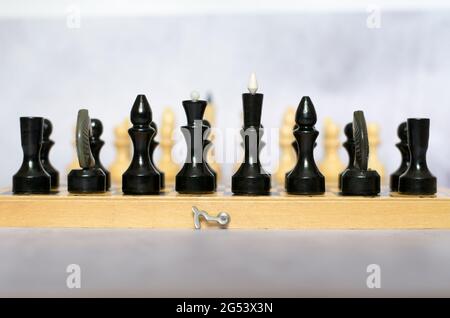 Schachfiguren auf Schachbrett-Seitenansicht, selektiver Fokus. Schwarze Stücke im Vordergrund, weiße Stücke im Hintergrund Stockfoto
