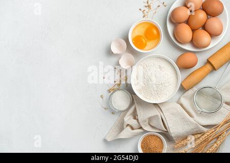 Zutaten für die Zubereitung von Teiggerichten: Kuchen, Kekse, Pizza, Pasta auf grauem Hintergrund. Mehl, Eier und Zucker. Draufsicht, Kopierbereich. Stockfoto