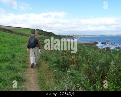 Rückansicht des Senior Walking Coastal Path mit Meerblick, Cornwall, Großbritannien Stockfoto