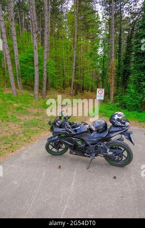 Mai 2021 Parma, Italien: Das Motorrad von Kawasaki parkte aus nächster Nähe über den Weg im Wald. Stockfoto