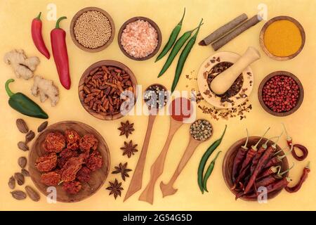 Frische & getrocknete Kräuter & Gewürzkollektion mit in Holzlöffeln, Schalen und Mörtel mit Stößel auf meliertem gelbem Hintergrund. Draufsicht. Stockfoto