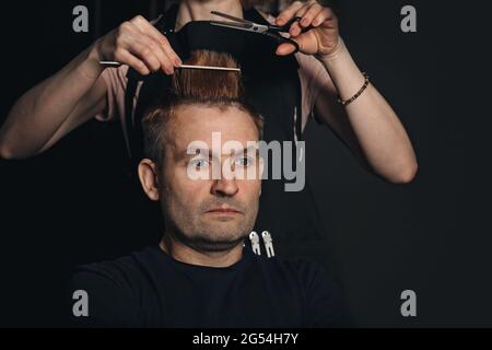 Neue trendige, moderne Frisur. Der Friseur scheren Männerhaare. Mann mittleren Alters im Friseurladen. Professionelle Frisur. Porträt eines gutaussehenden Mannes mit Modell Stockfoto