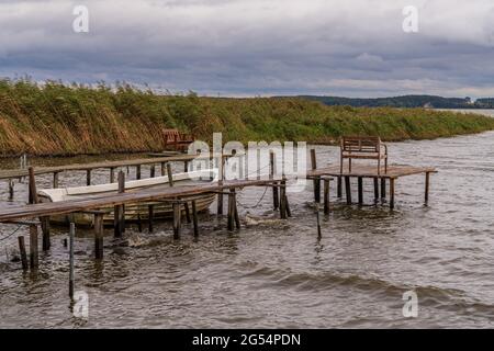 Eine hölzerne Seebrücke mit einem Boot und einigen Bänken an der Küste der Krumminer Wiek in Neeberg, Mecklenburg-Vorpommern, Deutschland Stockfoto