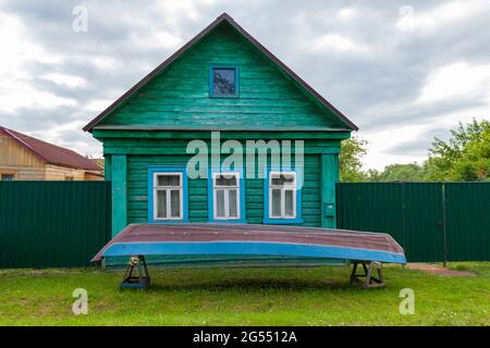 Ein altes Bauernhaus aus Holz mit einem umgedrehten Fischerboot davor. Stockfoto