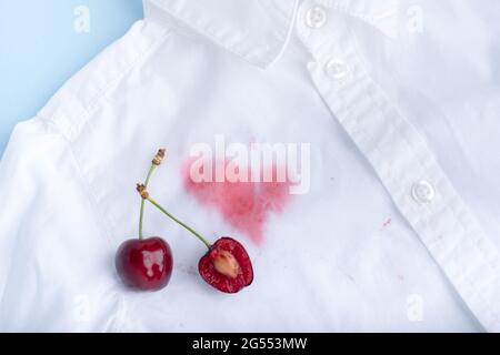 Kirschflecken von der Kleidung. Isoliert auf blauem Hintergrund. Hochwertige Fotos Stockfoto