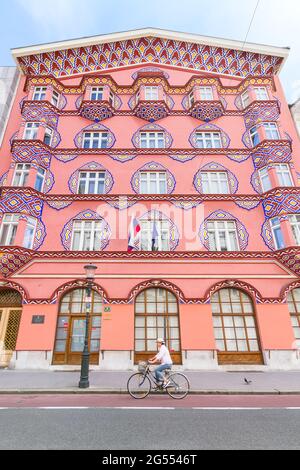 Ljubljana, Slowenien - 15. August 2018: Ein Radfahrer kommt an der farbenfrohen Fassade des Vurnik-Hauses oder der Genossenschaftsbank in der Innenstadt von Ljubljana vorbei Stockfoto