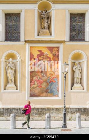 Ljubljana, Slowenien - 15. August 2018: Ein Mann kommt an einigen Kunstwerken an der Südfassade der Kathedrale von Ljubljana oder der St.-Nikolaus-Kirche vorbei Stockfoto