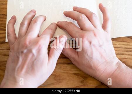 Point-of-View-Lesebuch mit Braille-Nahaufnahme auf einem bewaldeten Tisch Stockfoto