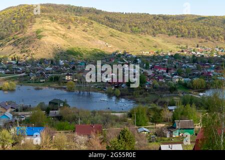 Eine kleine Stadt auf dem Hintergrund eines Flusses und Berge. Stockfoto