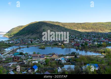 Eine kleine Stadt auf dem Hintergrund eines Flusses und Berge. Stockfoto