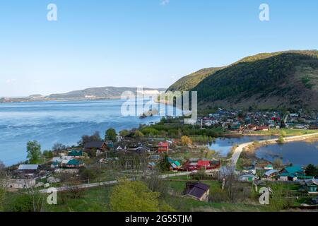 Eine kleine Stadt auf dem Hintergrund eines Flusses und Berge. Stockfoto