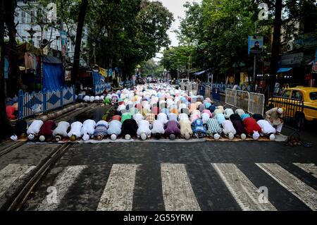 Menschen, die am Freitag Ramzan namaz auf einer Straße besuchen, während Fahrzeuge in der Nähe vorbeifahren. Kalkutta, Indien. Stockfoto