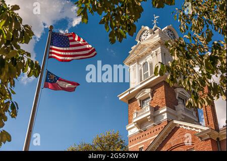 Die amerikanische Flagge und die Flagge des Staates Georgia winken vor dem historischen Gerichtsgebäude von Gwinnett auf dem Stadtplatz in Lawrenceville, Georgia. (USA) Stockfoto