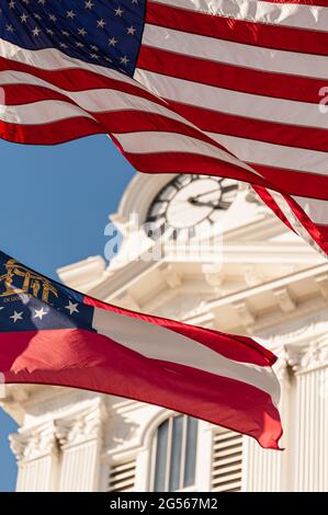 Die amerikanische Flagge und die Flagge des Staates Georgia winken vor dem historischen Gerichtsgebäude von Gwinnett auf dem Stadtplatz in Lawrenceville, Georgia. (USA) Stockfoto