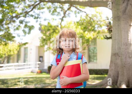 Kind mit Rucksäcken im Park in der Nähe der Schule stehen. Schüler mit Büchern und Rucksäcken im Freien. Schuljunge draußen in der Schule mit guter Zeit. Zurück zu Stockfoto