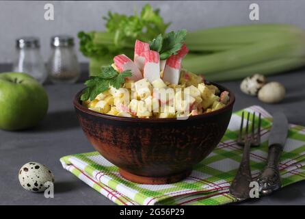 Salat mit Krabbenstäbchen, Sellerie, Apfel- und Wachteleiern in einer Schüssel auf grauem Hintergrund. Gesunde Ernährung. Stockfoto
