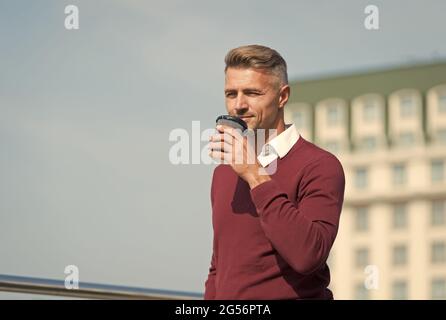 Unterwegs Kaffee trinken. Entspannen Sie sich und tanken Sie neue Kraft. Schöner Kerl halten Kaffee Tasse Himmel Hintergrund Kopie Raum. Harmonie und Gleichgewicht der Lebensenergie. Selbstversorgung Stockfoto