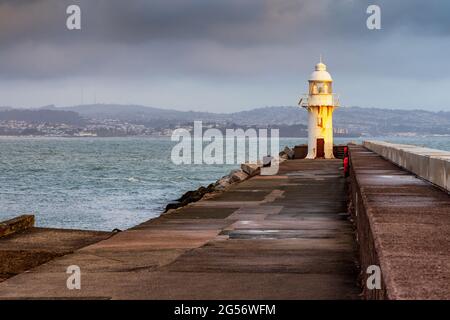 Der Leuchtturm am Ende des Wellenbrechers am Eingang zur Brixham Marina mit Blick auf Torbay in South Devon. Aufgenommen kurz nach Sonnenaufgang. Stockfoto