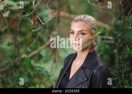 Mode an ungewöhnlichen Orten, Junge Frau in edgy Motorrad Jacke im Wald Stockfoto