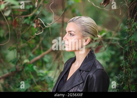 Mode an ungewöhnlichen Orten, Junge Frau in edgy Motorrad Jacke im Wald Stockfoto