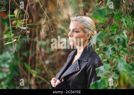 Mode an ungewöhnlichen Orten, Junge Frau in edgy Motorrad Jacke im Wald Stockfoto
