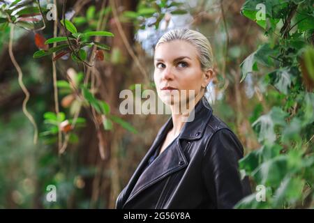 Mode an ungewöhnlichen Orten, Junge Frau in edgy Motorrad Jacke im Wald Stockfoto