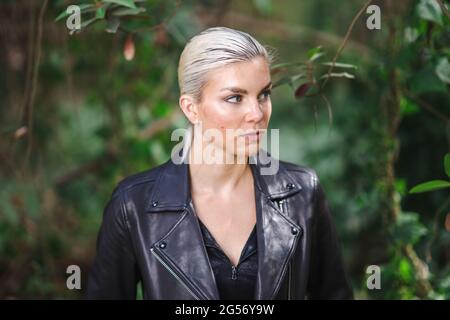 Mode an ungewöhnlichen Orten, Junge Frau in edgy Motorrad Jacke im Wald Stockfoto