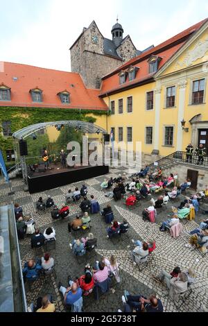 Ballenstedt, Deutschland. Juni 2021. 25. Juni 2021, Sachsen-Anhalt, Ballenstedt: Konzertbesucher sitzen im Hof des Schlossensembles. Mit der neuen Konzertreihe "Schlosstheater Open Air" kehrt die Kultur zum ersten Mal seit der Sperre in den Harz zurück. Im Harz finden erstmals neben Magdeburg und Halle kulturelle Veranstaltungen statt. Bei seinem ersten Konzert nach dem Lockdown präsentierte der Sänger Dirk Michaelis alte und neue bekannte Songs. Die Organisatoren der Konzertreihe im Schloss präsentieren Künstler wie den Stadtsänger Toni Krahl, Dieter Bier oder auch den Schauspieler Sk Stockfoto