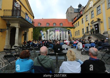 Ballenstedt, Deutschland. Juni 2021. 25. Juni 2021, Sachsen-Anhalt, Ballenstedt: Konzertbesucher sitzen im Hof des Schlossensembles. Mit der neuen Konzertreihe "Schlosstheater Open Air" kehrt die Kultur zum ersten Mal seit der Sperre in den Harz zurück. Im Harz finden erstmals neben Magdeburg und Halle kulturelle Veranstaltungen statt. Bei seinem ersten Konzert nach dem Lockdown präsentierte der Sänger Dirk Michaelis alte und neue bekannte Songs. Die Organisatoren der Konzertreihe im Schloss präsentieren Künstler wie den Stadtsänger Toni Krahl, Dieter Bier oder auch den Schauspieler Sk Stockfoto