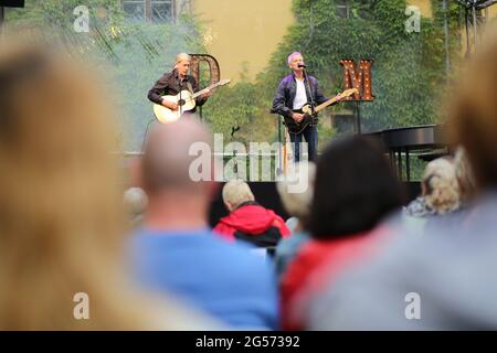 Ballenstedt, Deutschland. Juni 2021. 25. Juni 2021, Sachsen-Anhalt, Ballenstedt: Konzertbesucher sitzen im Hof des Schlossensembles. Mit der neuen Konzertreihe "Schlosstheater Open Air" kehrt die Kultur zum ersten Mal seit der Sperre in den Harz zurück. Im Harz finden erstmals neben Magdeburg und Halle kulturelle Veranstaltungen statt. Bei seinem ersten Konzert nach dem Lockdown präsentierte der Sänger Dirk Michaelis alte und neue bekannte Songs. Die Organisatoren der Konzertreihe im Schloss präsentieren Künstler wie den Stadtsänger Toni Krahl, Dieter Bier oder auch den Schauspieler Sk Stockfoto