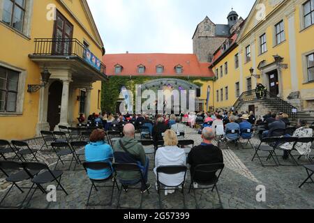 Ballenstedt, Deutschland. Juni 2021. 25. Juni 2021, Sachsen-Anhalt, Ballenstedt: Konzertbesucher sitzen im Hof des Schlossensembles. Mit der neuen Konzertreihe "Schlosstheater Open Air" kehrt die Kultur zum ersten Mal seit der Sperre in den Harz zurück. Im Harz finden erstmals neben Magdeburg und Halle kulturelle Veranstaltungen statt. Bei seinem ersten Konzert nach dem Lockdown präsentierte der Sänger Dirk Michaelis alte und neue bekannte Songs. Die Organisatoren der Konzertreihe im Schloss präsentieren Künstler wie den Stadtsänger Toni Krahl, Dieter Bier oder auch den Schauspieler Sk Stockfoto