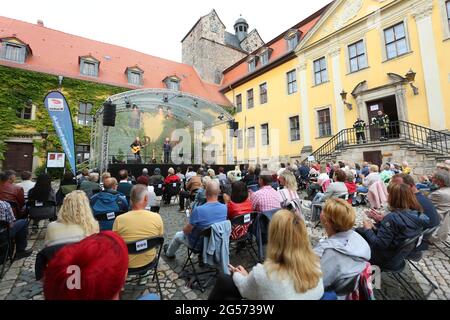 Ballenstedt, Deutschland. Juni 2021. 25. Juni 2021, Sachsen-Anhalt, Ballenstedt: Konzertbesucher sitzen im Hof des Schlossensembles mit der neuen Konzertreihe "Schlosstheater Open Air" kehrt die Kultur erstmals seit der Sperrung in den Harz zurück. Erstmals finden im Harz neben Magdeburg und Halle kulturelle Veranstaltungen statt. Bei seinem ersten Konzert nach dem Lockdown präsentierte der Sänger Dirk Michaelis alte und neue bekannte Songs. Die Organisatoren der Konzertreihe im Schloss präsentieren Künstler wie den Stadtsänger Toni Krahl, Dieter Bier oder auch Stockfoto