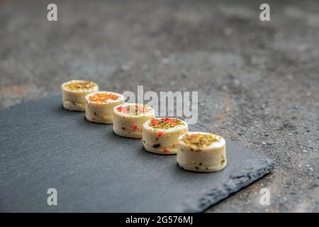 Käseplatte mit Gewürzen. Mazzarella Käse mit verschiedenen Gewürzen. Käsesnacks verschiedener Geschmacksrichtungen auf einem Tablett aus schwarzem Stein. Hintergrund oder Banner auf t Stockfoto